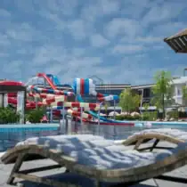 Relaxing pool area at Holidays Park Resort with water slides and sun loungers. Perfect for family fu.