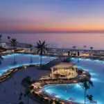 Luxury pool area at sunset in Hurghada, Egypt, with ocean views and palm trees.