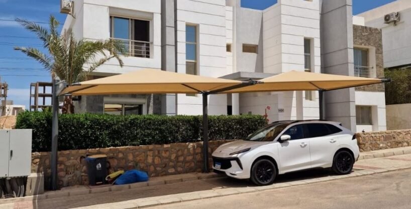 Luxury modern white villas with shaded car park and green landscaping under a bright blue sky, ideal property.