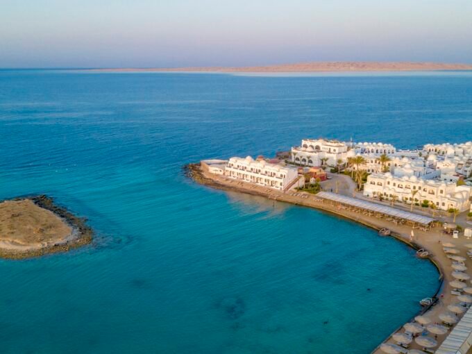Aerial drone view of Hurghada Red Sea coast with beach resort, turquoise water, palm trees, and hotel complex — Intercontinental District area, Egypt