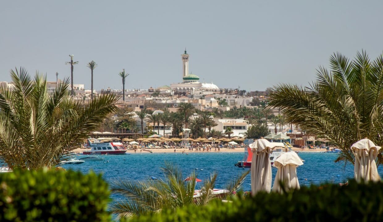 Beach view with Hurghada skyline and marina in the background.
